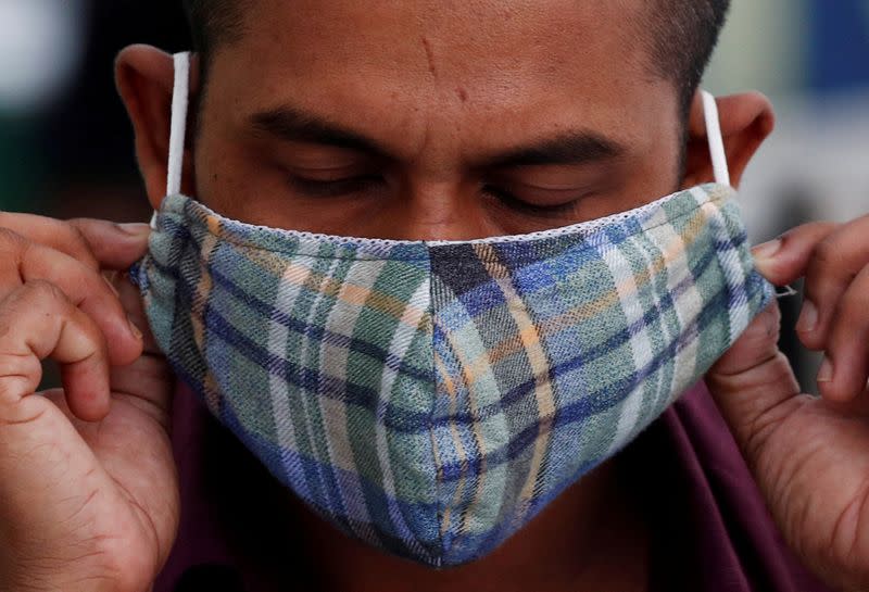 FILE PHOTO: A migrant worker puts on a mask at a dormitory, amid the coronavirus disease (COVID-19) outbreak in Singapore