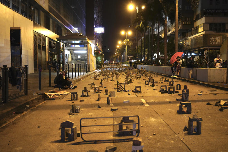 Protestors rest near a road barricaded with bricks in Hong Kong, early Tuesday, Nov. 19, 2019. About 100 anti-government protesters remained holed up at a Hong Kong university Tuesday as a police siege of the campus entered its third day. (AP Photo/Vincent Yu)