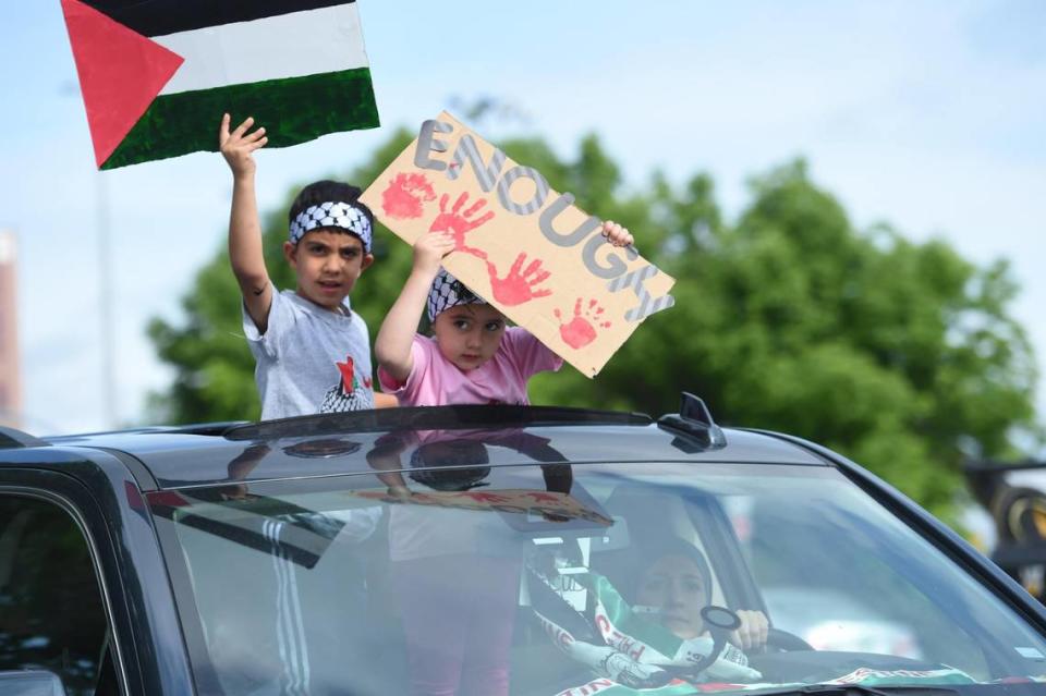 Children in a passing car held signs for KC Rally as Palestinians and supporters gathered Saturday, May 15, on the Country Club Plaza to show support for Palestinian human rights and to condemn violence against Palestinians in Gaza and the Middle East.