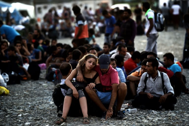 A Syrian couple waits with other migrants for the train near a train station at the F.Y.R. of Macedonia's village of Gevgelija on August 29, 2015