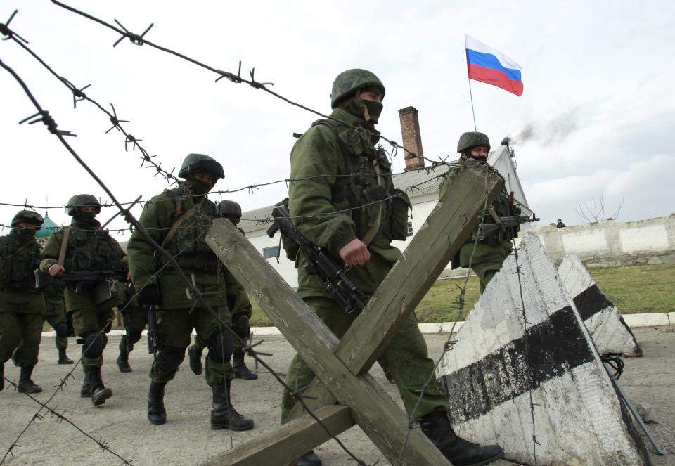 Military personnel, believed to be Russian servicemen, march outside the territory of a Ukrainian military unit in the village of Perevalnoye outside Simferopol