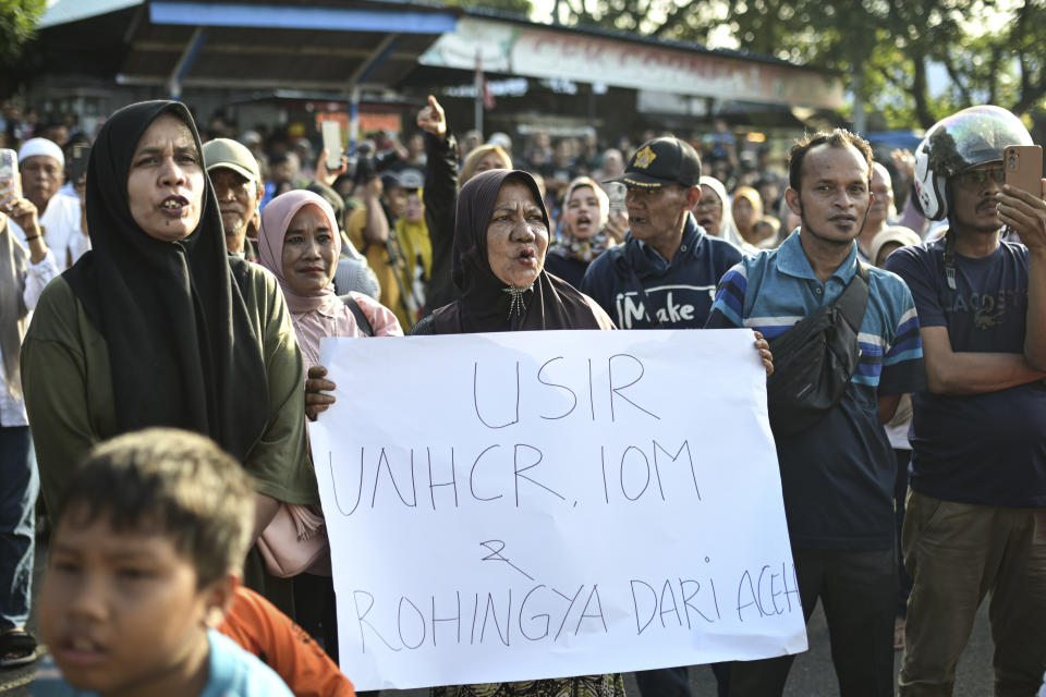 A woman holds up a poster reading "Kick out UNHCR, IOM and the Rohingyas from Aceh" during a rally in Sabang, Aceh province, Indonesia, Monday, Dec. 18, 2023. More than 200 people have protested against the continued arrival of Rohingya refugees by boat on an island in Indonesia. Over 1,500 Rohingya who fled violent attacks in Myanmar and are leaving camps in Bangladesh have arrived in Aceh off the tip of Sumatra since November. (AP Photo/Reza Saifullah)