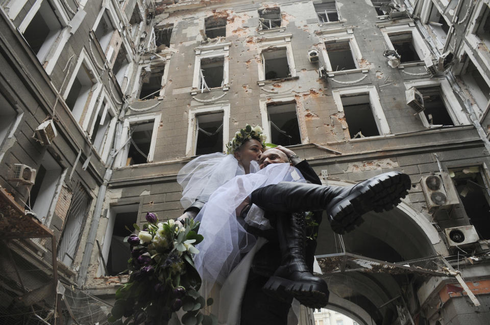 Volunteers Anastasia, left, and Anton pose for a picture in a yard of an apartment building destroyed by shelling during their wedding celebration in Kharkiv, Ukraine, Sunday, April 3, 2022. (AP Photo/Andrew Marienko)