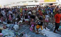 Residents watch as others grab looted goods thrown from the second floor of a warehouse in the town of Guiuan, Eastern Samar province in the central Philippines on November 11, 2013