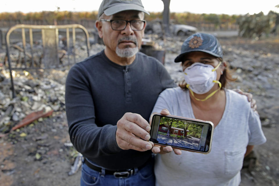 Justo and Bernadette Laos show a photo of the home they rented that was destroyed by the Kincade Fire near Geyserville, Calif., Thursday, Oct. 31, 2019. The fire started last week near the town of Geyserville in Sonoma County north of San Francisco. (AP Photo/Charlie Riedel)