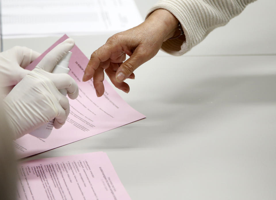 A member of the electoral commission sprays an indelible liquid on the finger of a voter at a polling station in Belgrade, Serbia, Sunday, June 21, 2020. Serbia’s ruling populists are set to tighten their hold on power in a Sunday parliamentary vote held amid concerns over the spread of the coronavirus and a partial boycott by the opposition. Nearly 6.6 million voters are eligible to cast ballots for the 250-member parliament and local authorities. (AP Photo/Darko Vojinovic)