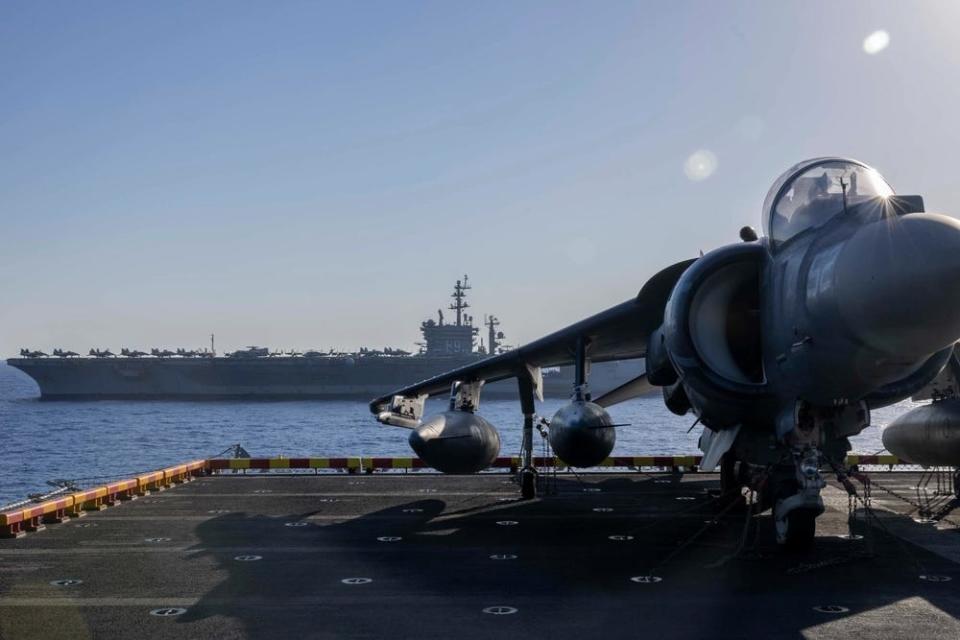 A fighter jet is seen aboard the amphibious assault ship USS Wasp with the aircraft carrier USS Dwight D. Eisenhower in the distance.