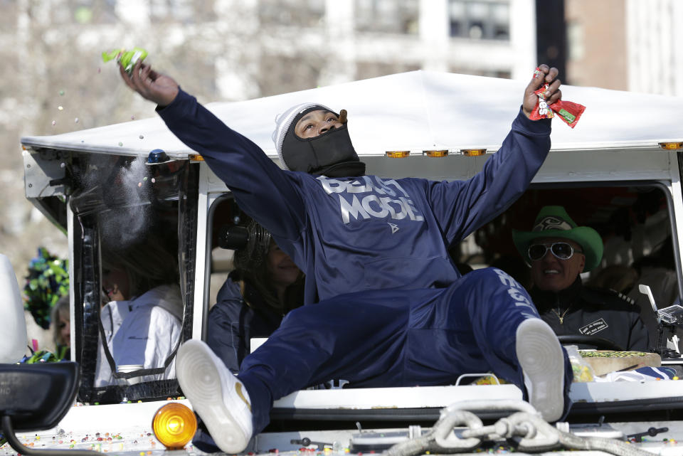 Seattle Seahawks' running back Marshawn Lynch throws pieces of Skittles candy while riding on the hood of a vehicle during the Super Bowl champions parade on Wednesday, Feb. 5, 2014, in Seattle. The Seahawks beat the Denver Broncos 43-8 in NFL football's Super Bowl XLVIII on Sunday. (AP Photo/Elaine Thompson)