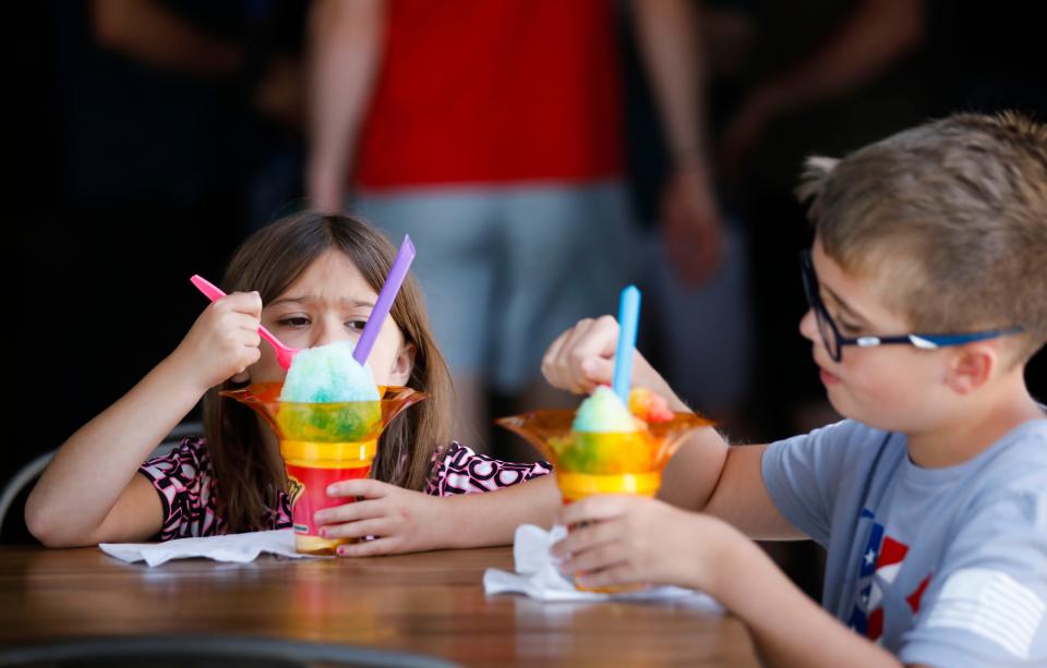 Audrey, 6, and Phillip, 11, Johnson eat shave ice from vendor Sno Biz at 14 Mill Market, a new food hall and entertainment venue in Nixa, on Tuesday, June 13, 2023.
