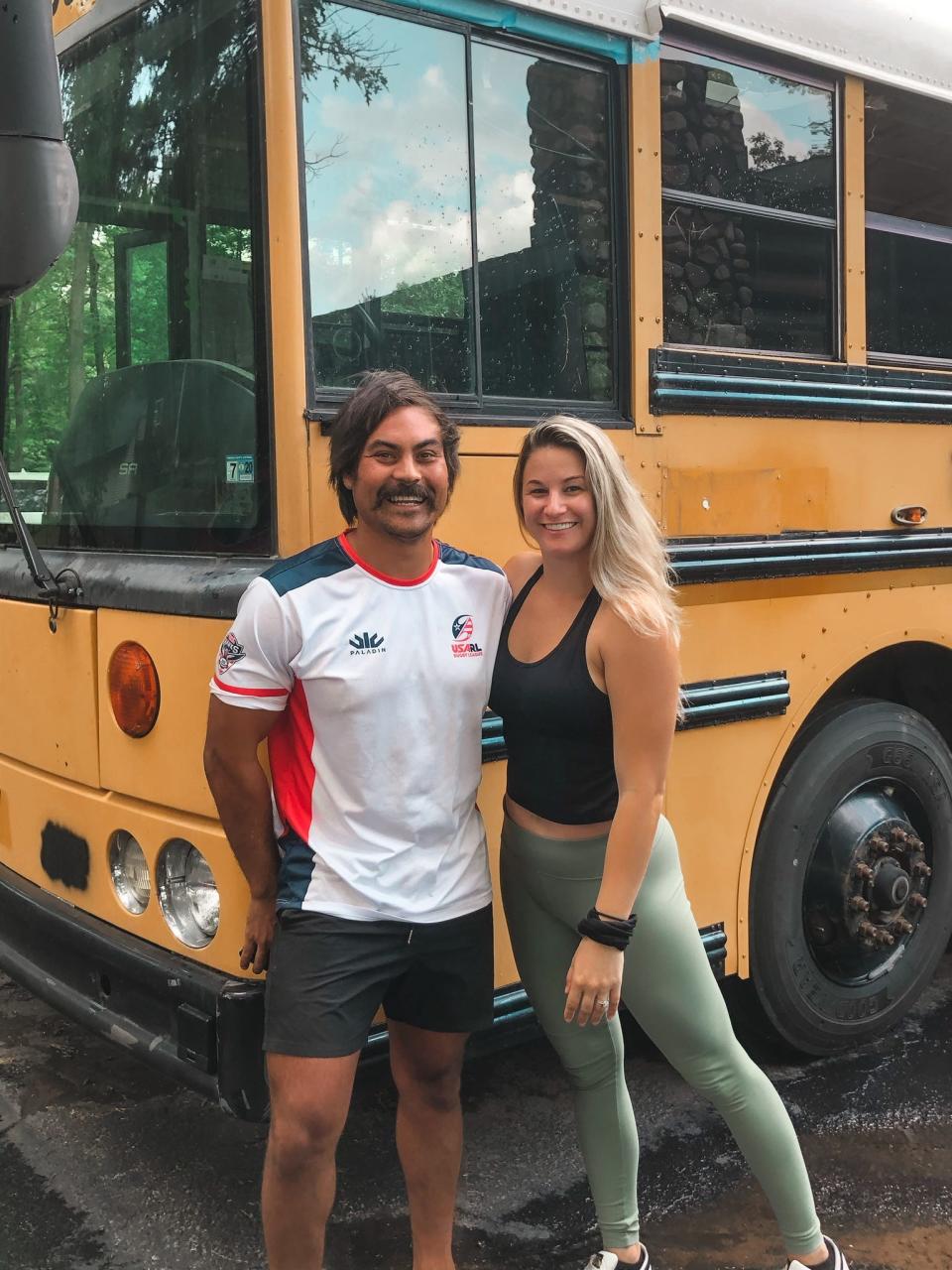 The writer and her partner standing outside their original yellow school bus