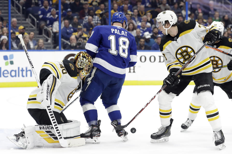 Tampa Bay Lightning left wing Ondrej Palat (18) crashes into Boston Bruins goaltender Tuukka Rask (40) as defenseman Charlie McAvoy (73) defends during the second period of an NHL hockey game Thursday, Dec. 12, 2019, in Tampa, Fla. (AP Photo/Chris O'Meara)