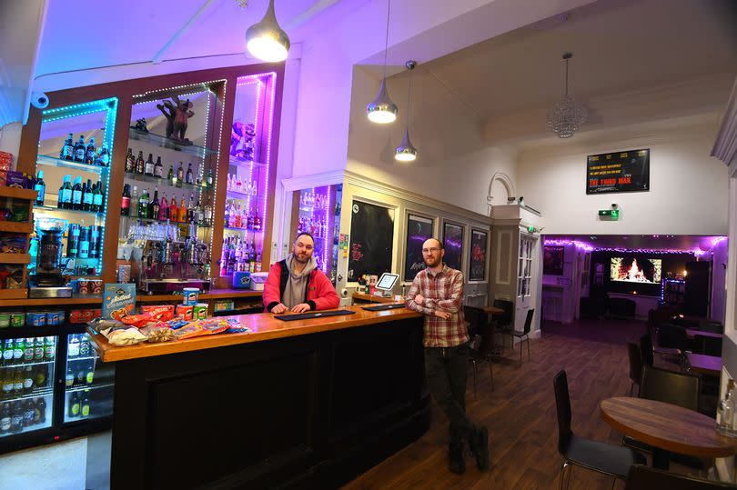 Two young men standing by a well appointed bar area at Southport Bijou Cinema. They are staff members Andy Harrison and Phil Pierce.