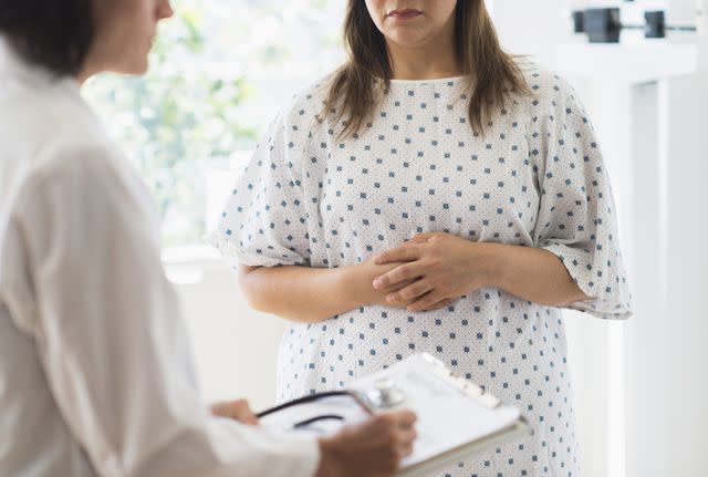 Tetra Images / Getty Images Stock image of a woman with her arms crossed over her stomach consulting with a doctor