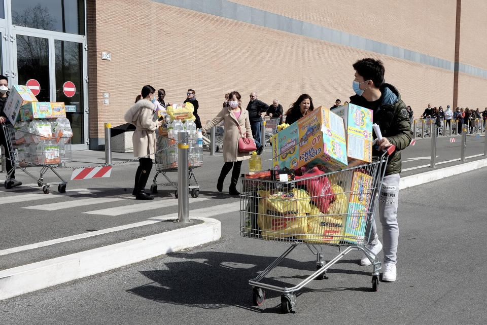 People wearing face masks queuing up at supermarkets to stock up on food and goods in Rome, Italy. (Credit: Simona Granati/Getty Images)