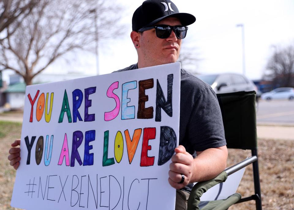 Kody Macaulay holds a sign outside Owasso High School during a February demonstration in honor of Nex Benedict. Dozens of people called on school and state officials to better protect LGBTQ+ students.