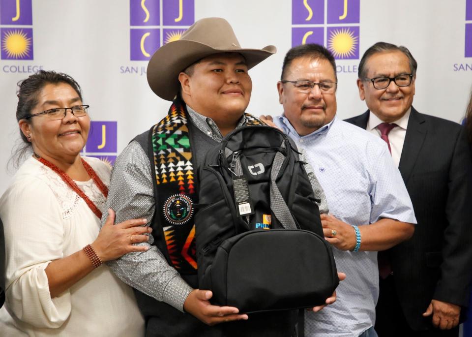 Navajo Technical University student Lyle Ben, center, stands with his mother, Alicia Ben, left, and his father Lawrence Ben, right, and NTU President Elmer Guy, far right, during the graduation ceremony on May 10 in Farmington to recognize scholarship recipients under the Public Service Company of New Mexico's Navajo Nation Workforce Training Initiative.