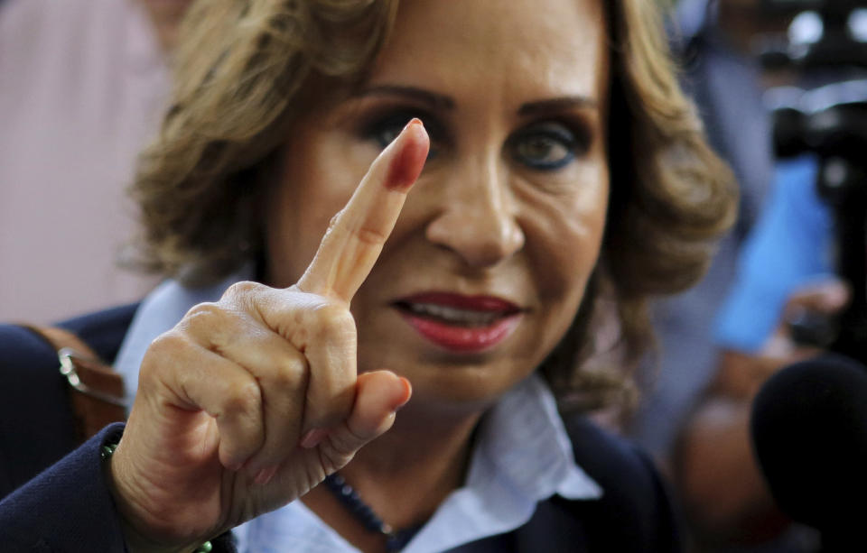 Sandra Torres, presidential candidate of the National Unity of Hope party, UNE, shows her ink stained finger to the press after casting her vote during general elections in Guatemala City, Sunday, June 16, 2019. Guatemalans are voting for their next president in elections plagued by widespread disillusion and distrust, and as thousands of their compatriots flee poverty and gang violence to seek a new life in the United States. The former first lady is expected to finish first but without enough votes to win in the first round. (AP Photo/Oliver de Ros)