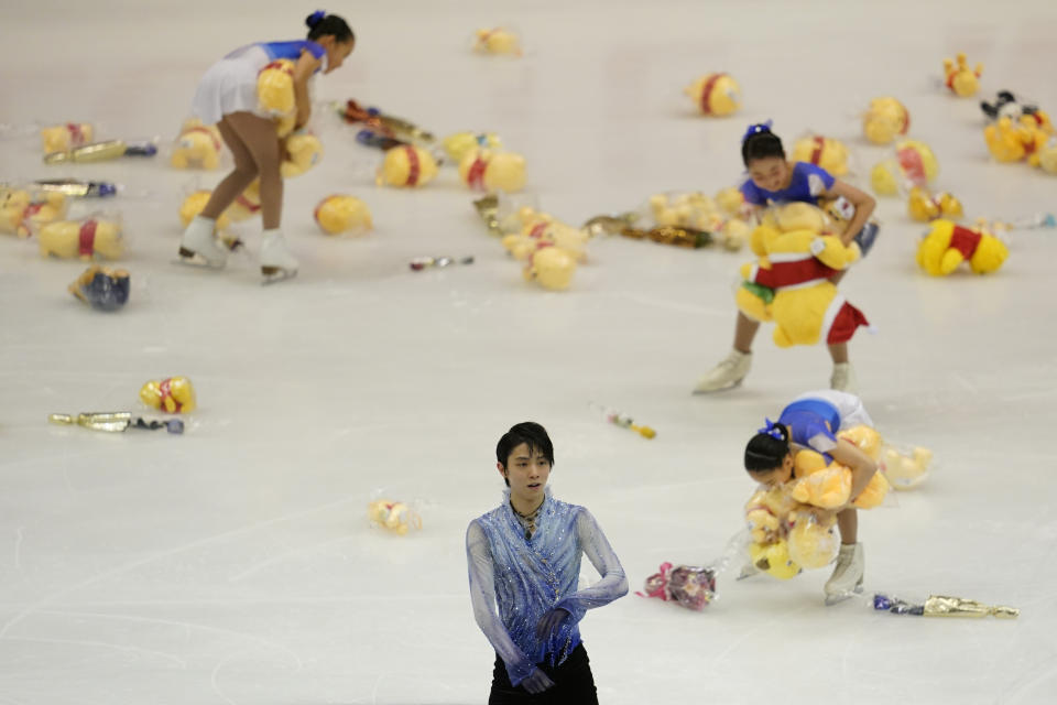 Yuzuru Hanyu of Japan acknowledges the crowd after his men's short program as skating girls collect flowers and toys thrown from fans during the ISU Grand Prix of Figure Skating in Sapporo, northern Japan, Friday, Nov. 22, 2019. (AP Photo/Toru Hanai)