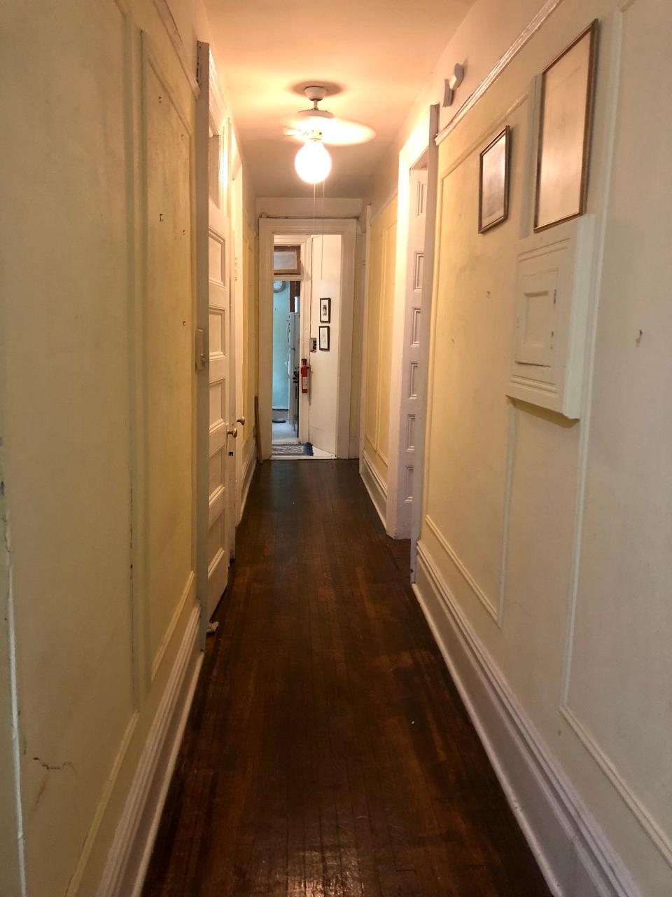 A dark hallway with wood floors.