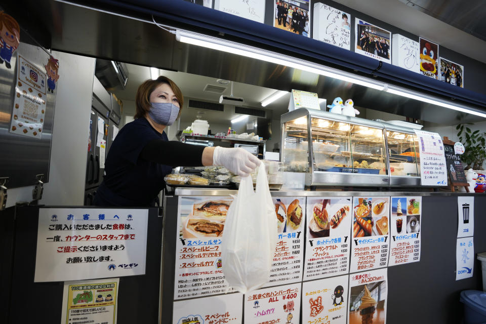 Fast-food restaurant owner Atsuko Yamamoto takes care of her customer at her shop, Penguin, in Futaba Business Incubation and Community Center in Futaba town, northeastern Japan, Wednesday, March 2, 2022. Yamamoto restarted Penguin, one of her family's old businesses, in 2020, when the community center opened for the public, as she wanted to help bring local people back together, as part of her way of the area reconstruction, following the 2011 earthquake. (AP Photo/Hiro Komae)