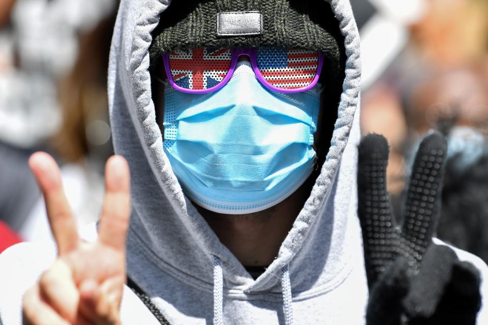 A demonstrator, wearing PPE (personal protective equipment), including a face mask as a precautionary measure against COVID-19, and sunglasses themed on the Union and US flags, gestures during a protest march in Manchester, northern England, on June 6, 2020, to show solidarity with the Black Lives Matter movement in the wake of the killing of George Floyd, an unarmed black man who died after a police officer knelt on his neck in Minneapolis. - The United States braced Friday for massive weekend protests against racism and police brutality, as outrage soared over the latest law enforcement abuses against demonstrators that were caught on camera. With protests over last week's police killing of George Floyd, an unarmed black man, surging into a second weekend, President Donald Trump sparked fresh controversy by saying it was a "great day" for Floyd. (Photo by Paul ELLIS / AFP) (Photo by PAUL ELLIS/AFP via Getty Images)