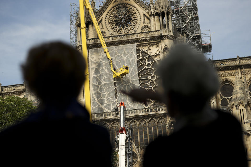 Workers, top, fix a net to cover one of the iconic stained glass windows of the Notre Dame Cathedral in Paris, Sunday, April 21, 2019. The fire that engulfed Notre Dame during Holy Week forced worshippers to find other places to attend Easter services, and the Paris diocese invited them to join Sunday's Mass at the grandiose Saint-Eustache Church on the Right Bank of the Seine River. (AP Photo/Francisco Seco)