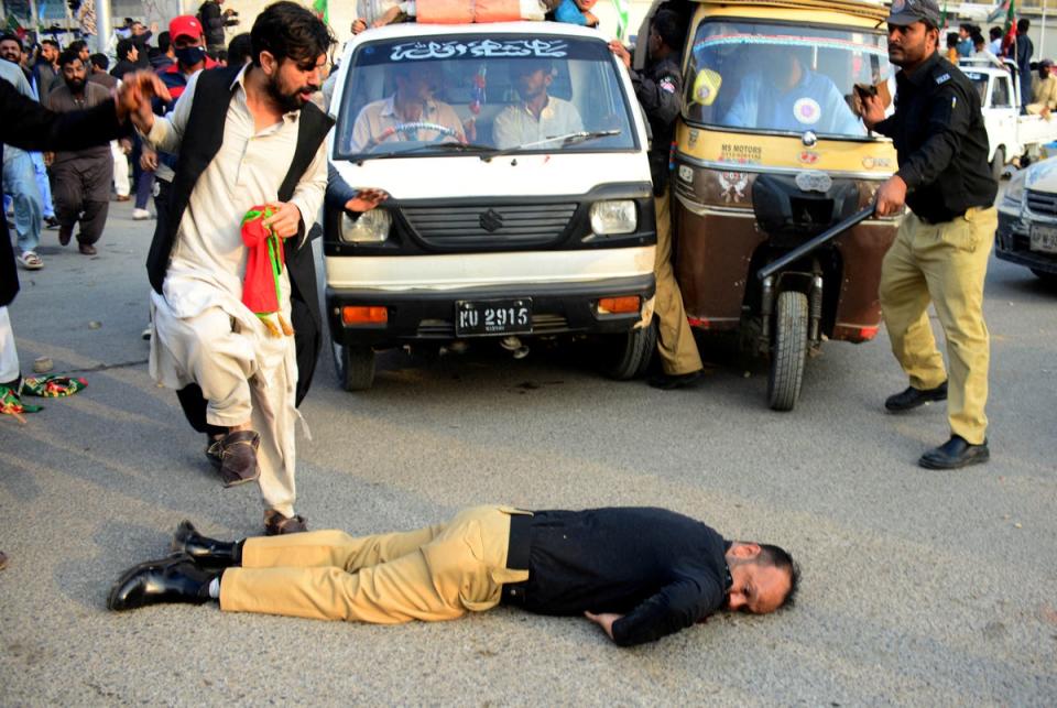 An injured police officer lies on the road during a clash with supporters of former PM Khan's party, the Pakistan Tehreek-e-Insaf, in Karachi (REUTERS)