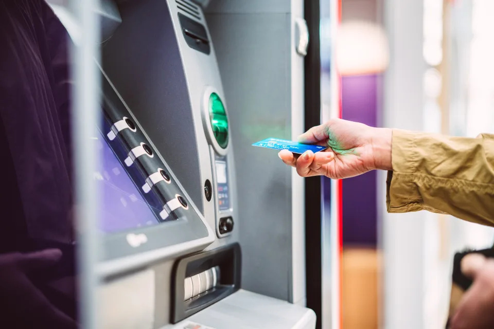 Person using an ATM, inserting a card into the machine