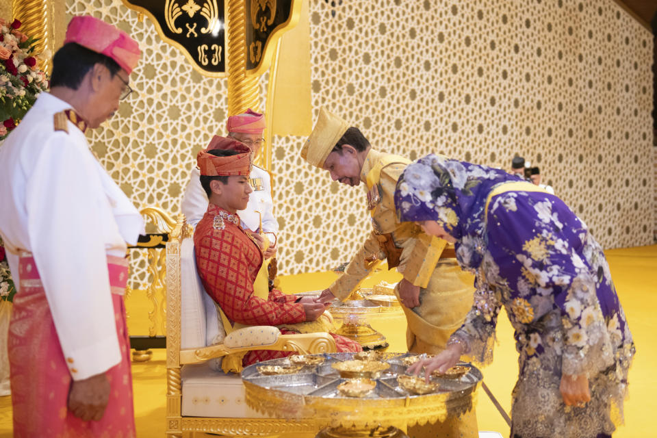 This picture taken by Brunei's Information Department on Jan. 10, 2024 shows Brunei's Sultan Hassanal Bolkiah, centre right, greeting Brunei's Prince Abdul Mateen's, center, during the royal powdering ceremony at Istana Nurul Iman, ahead of his wedding to Anisha Rosnah, in Bandar Seri Begawan, Brunei. (Brunei's Information Department via AP)