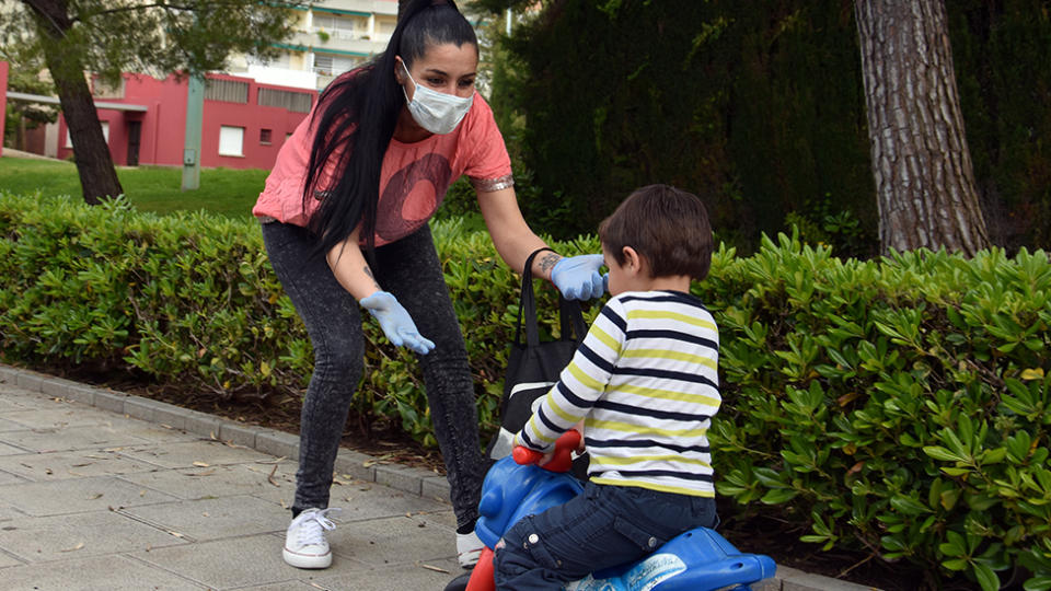 A mum wearing a mask is seen playing with her son. Source: AAP