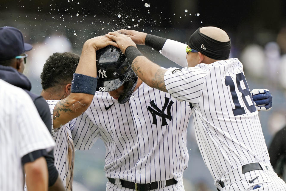 New York Yankees Gleyber Torres, left, and Rougned Odor, right, surround New York Yankees designated hitter Aaron Judge, center, after Judge drew a bases-loaded game-winning walk in a baseball game against the Chicago White Sox, Sunday, May 23, 2021, at Yankee Stadium in New York. The Yankees defeated the White Sox 5-4. (AP Photo/Kathy Willens)