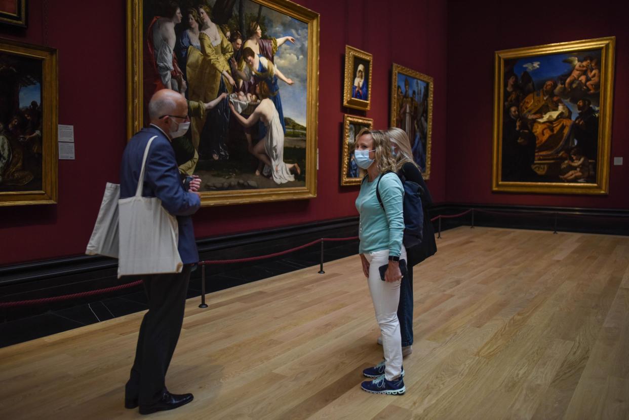 A group of people are seen wearing masks while viewing paintings at the National Portrait Gallery during a press preview ahead of the gallery's reopening on July 4, 2020, in London, England. The National Portrait gallery is set to re-open on July 8 following closure due to the coronavirus pandemic.