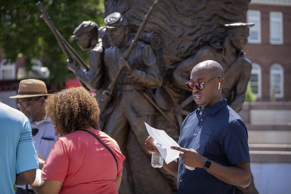 Associated Press reporter Darren Sands, right, reads the names of United States Colored Troops regimental soldiers, including his great-great-great-great grandfather Hewlett Sands, at the African American Civil War Memorial as part of Juneteenth commemorations on Wednesday, June 19, 2024, in Washington. (AP Photo/Mark Schiefelbein)