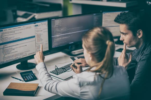 Two people looking at software code