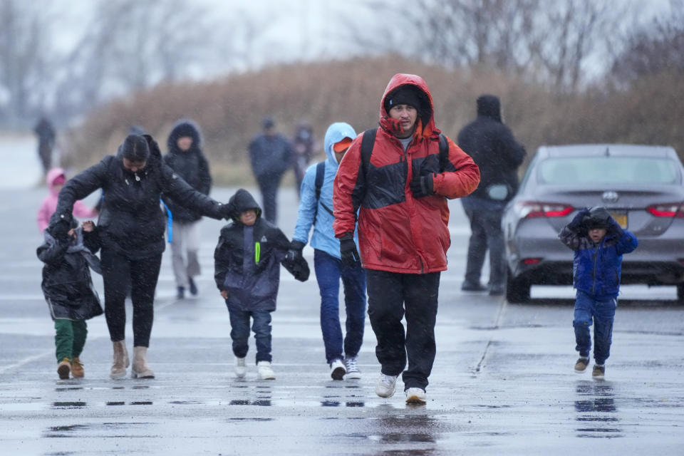 Immigrants run in the rain towards the tents at migrant housing location at Floyd Bennett Field, Tuesday, Jan. 9, 2024, in the Brooklyn borough in New York. New York City will evacuate the nearly 2000 immigrants housed in tents at the site due to an impending winter storm. (AP Photo/Mary Altaffer)