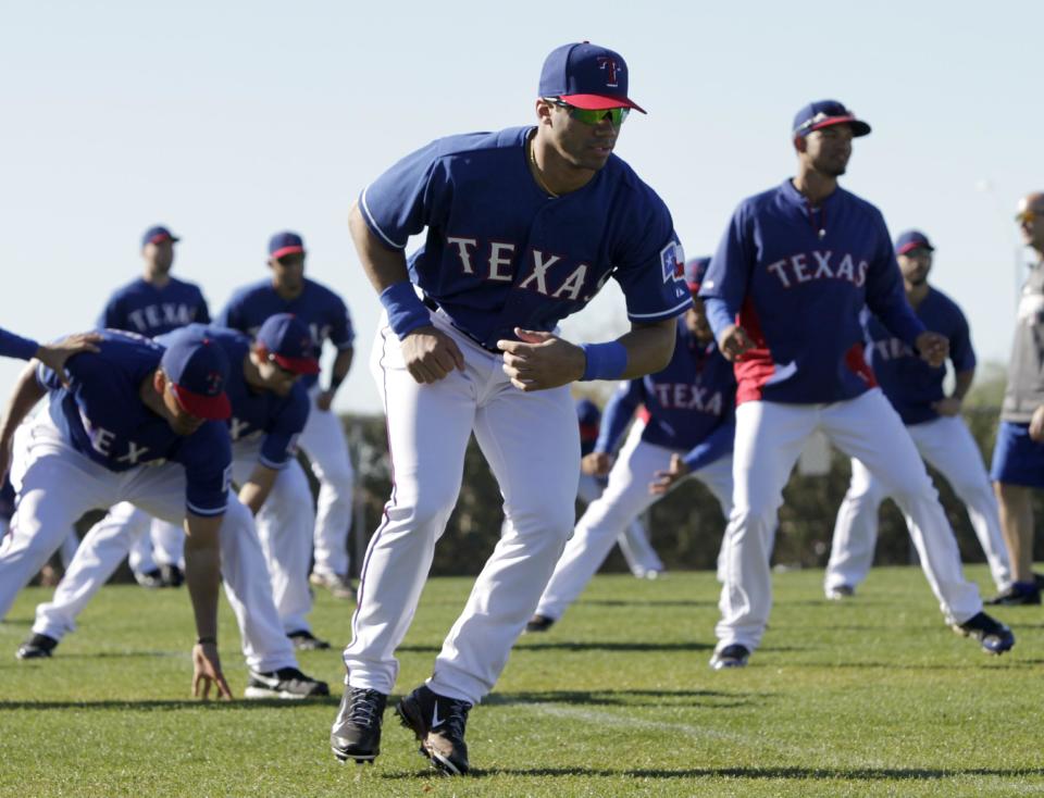 Seattle Seahawks quarterback Russell Wilson, center, runs through morning stretches with the Texas Rangers during spring training baseball practice, Monday, March 3, 2014, in Surprise, Ariz. (AP Photo/Tony Gutierrez)