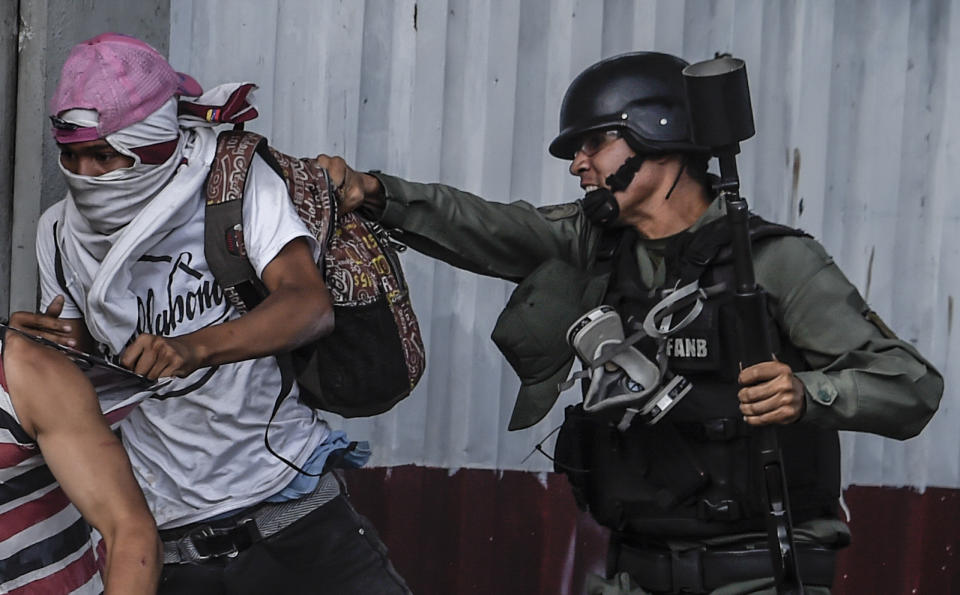 <p>An anti-government activist is grabbed by a member of the National Guard during clashes in Caracas on July 27, 2017 on the second day of a 48-hour general strike called by the opposition. (Photo: Juan Barreto/AFP/Getty Images) </p>