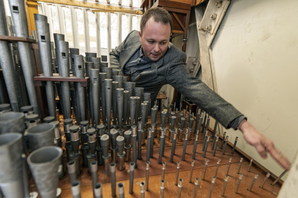 Kevin Cartwright, technician and president of Los Angeles-based Rosales Organ Builders, who has been contracted to maintain the Hazel Wright organ, pulls up one of its smallest pipes at Christ Cathedral in Garden Grove, Calif., Tuesday, Feb. 15, 2022. "The organ must be tuned for the building," he said. "Each pipe must be individually tuned." That means Cartwright must climb up ladders several stories high to reach every pipe and tune each one to perfection. (AP Photo/Damian Dovarganes)