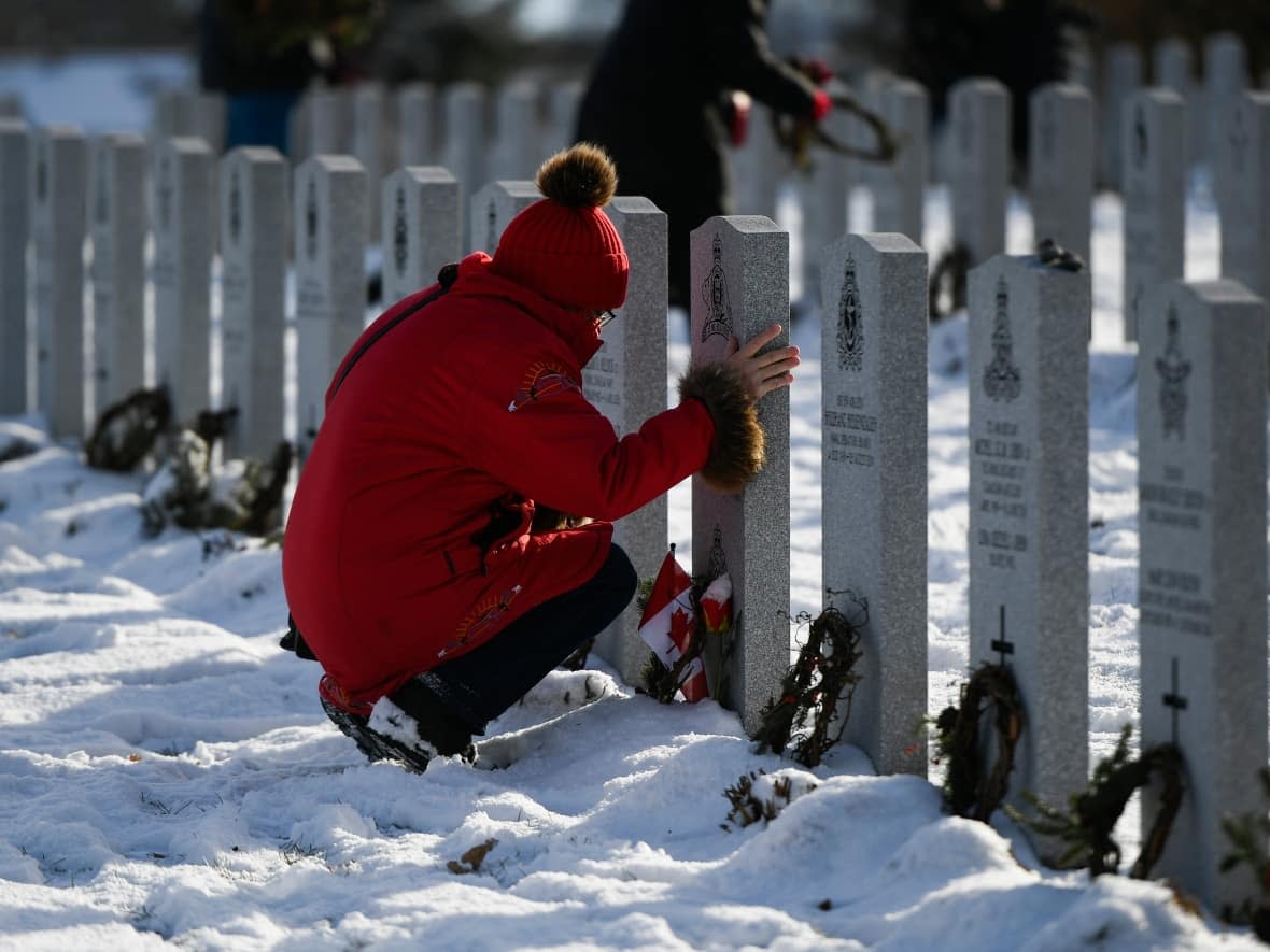 Veteran Laura Wooldridge touches the gravestone of her husband Gilbert Barre, who served with the Royal 22nd Regiment, after laying a wreath, at the National Military Cemetery in Ottawa, on Sunday. (Justin Tang/Canadian Press - image credit)