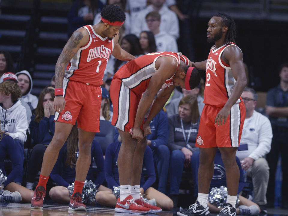 Ohio State's Jamison Battle, center, is checked on by teammates Roddy Gayle Jr. (1) and Bruce Thornton (2) after going to the floor while fighting for a loose ball during the first half of the team's NCAA college basketball game against Penn State on Saturday, Dec 9, 2023, in State College, Pa. (AP Photo/Gary M. Baranec)