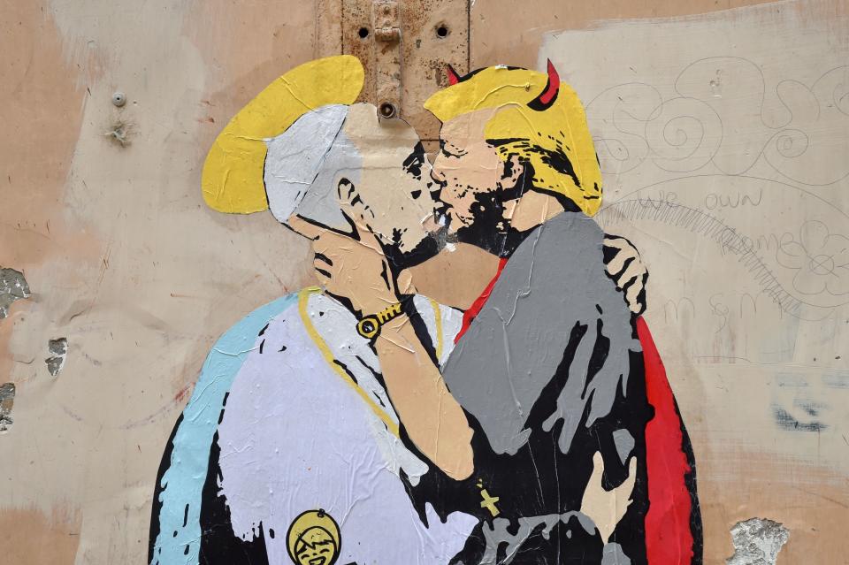 A collage shows Pope Francis kissing US President Donald Trump with a caption by Italian artist TvBoy reading in English and Italian 'The Good forgives the Evil' in tiny letters along Francis belt, on May 11, 2017 near Castel Sant'Angelo in central Rome.