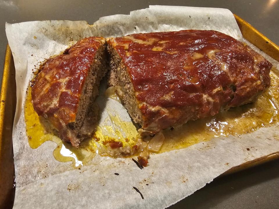 Meatloaf covered in ketchup cut open on a sheet of parchment