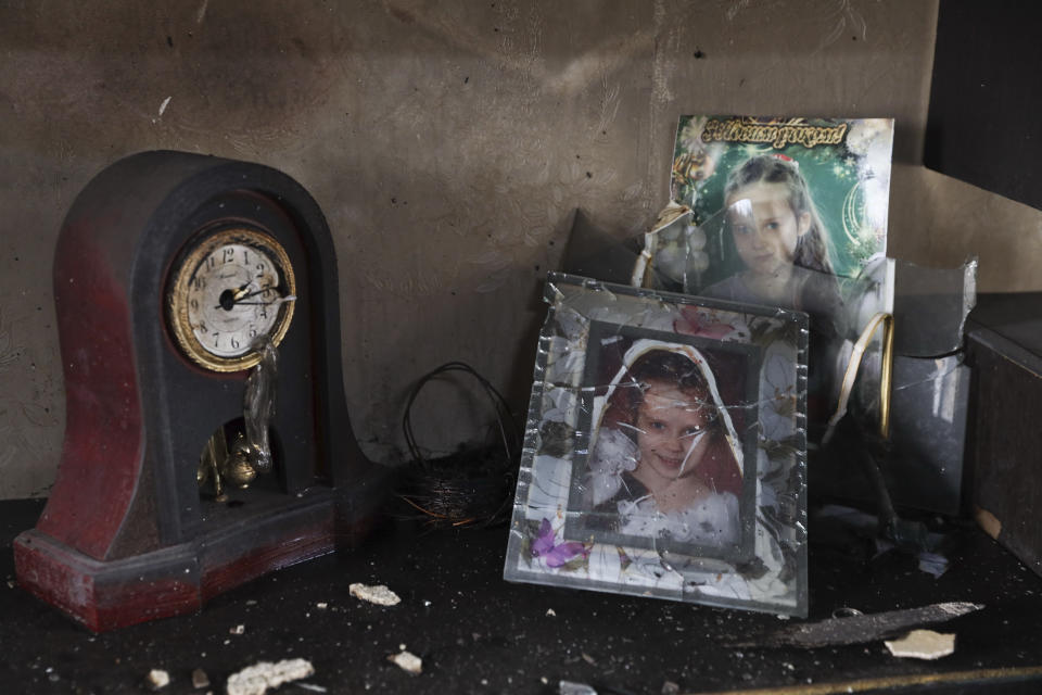 Portraits of an 11-year old girl killed by a Russian missile stand near the clock that stopped in the rocket attack in a damaged house in Zaporizhzhia, Ukraine, Sunday, April 9, 2023. AP Photo/Kateryna Klochko)