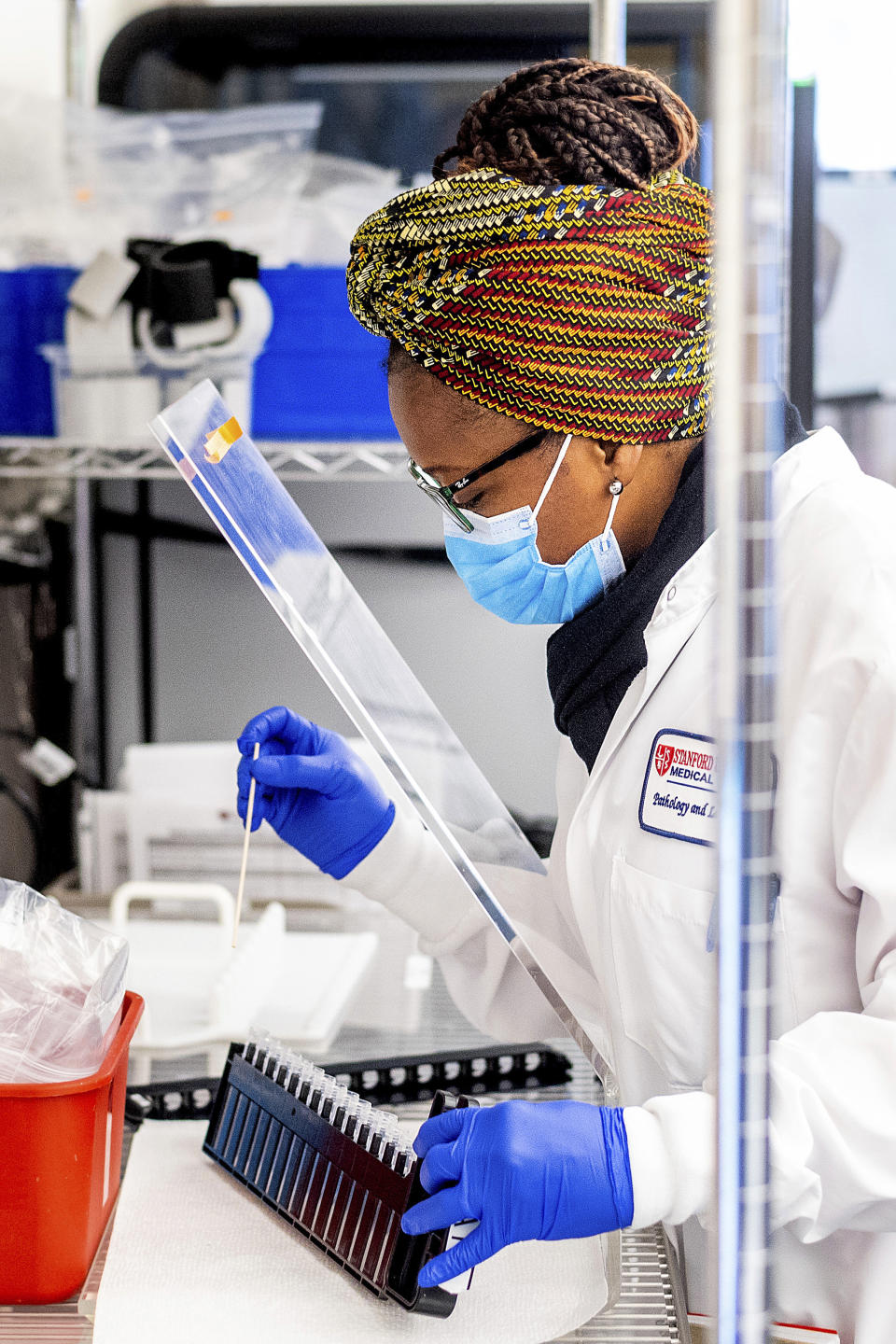 Clinical lab scientist Carine Pokam processes upper respiratory samples from patients suspected of having COVID-19 at the Stanford Clinical Virology Laboratory on Wednesday, Feb. 3, 2021, in Palo Alto, Calif. Viruses mutate constantly. To stay ahead of the threat, scientists analyze samples for genetic changes, watching closely for ones that might make the virus more infectious or more deadly. (AP Photo/Noah Berger)