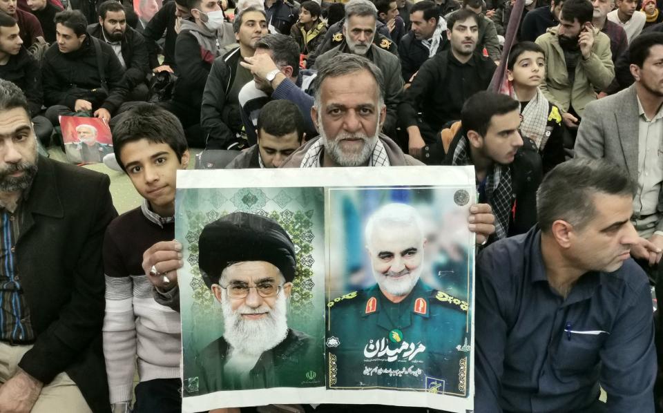 A man in Tehran holds a portraits of Ayatollah Ali Khamenei, Iran's Supreme Leader, and Qassim Soleimani at the ceremony in honour of the killed terrorist chief