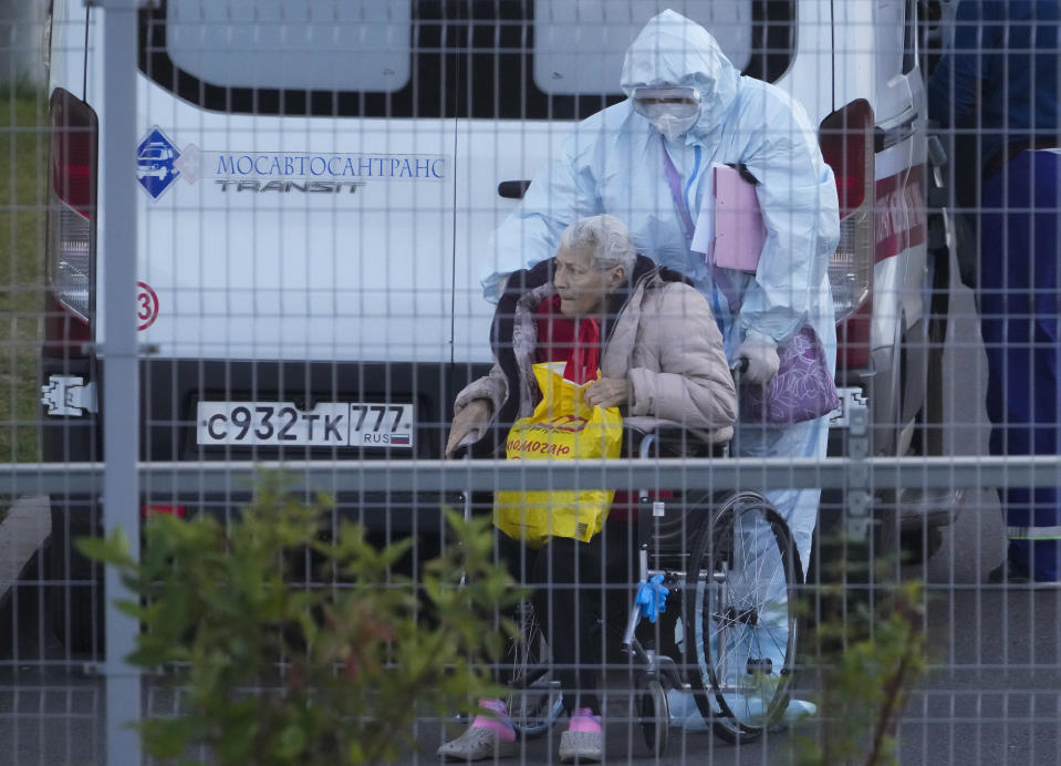 A medical worker wearing protective gear transports a patient suspected of having coronavirus in a wheelchair at a hospital in Kommunarka, outside Moscow, Russia, Monday, Oct. 11, 2021. Russia's daily coronavirus infections and deaths are hovering near all-time highs amid a laggard vaccination rate and the Kremlin's reluctance to toughen restrictions. Russia's state coronavirus task force reported 29,409 new confirmed cases Monday. That's the highest number since the start of the year and just slightly lower than the pandemic record reached in December. (AP Photo/Alexander Zemlianichenko)