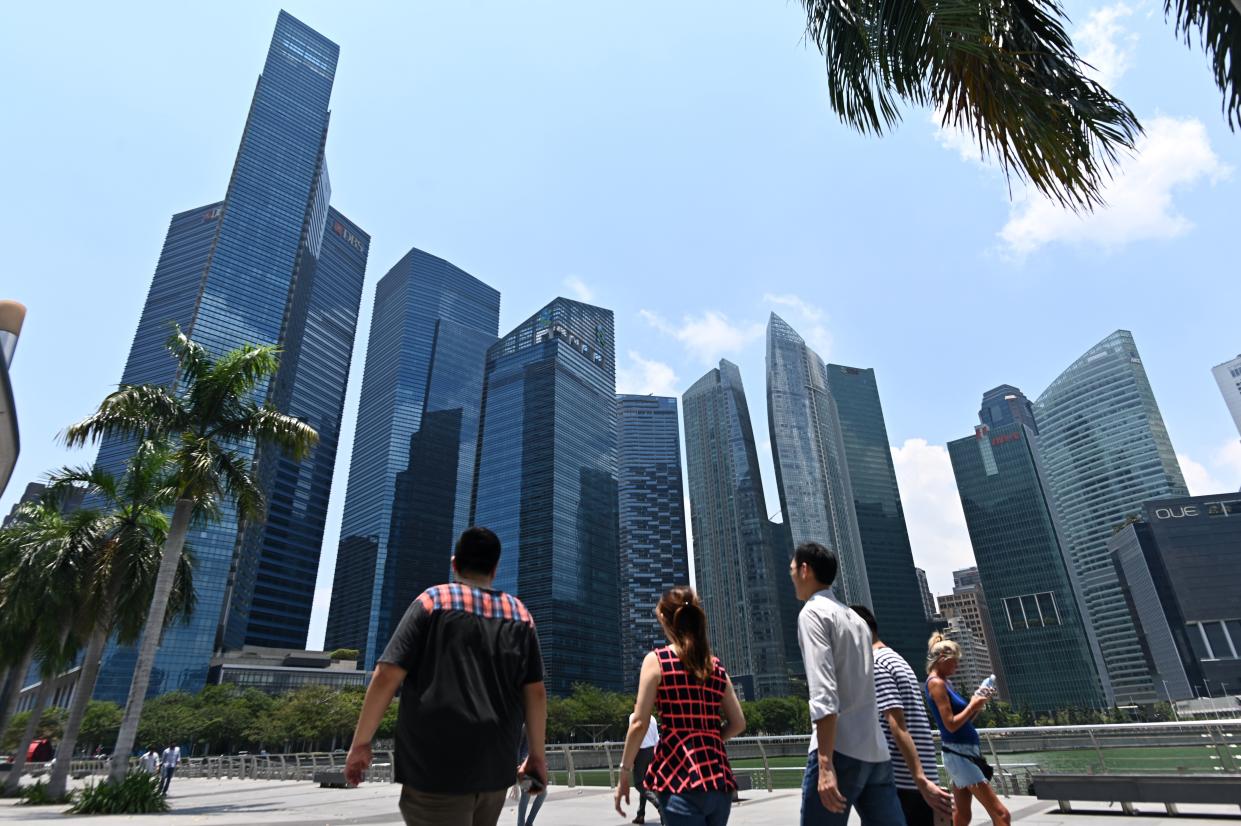 People walk along a promenade with a view of Marina Bay financial centre in Singapore on March 8, 2019. (Photo by Roslan RAHMAN / AFP)        (Photo credit should read ROSLAN RAHMAN/AFP/Getty Images)