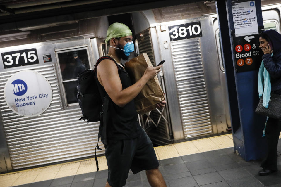 A commuter wears a face mask in the New York City transit system, Monday, March 9, 2020, in New York. New York continued grappling Monday with the new coronavirus, as case numbers, school closings and other consequences grew. (AP Photo/John Minchillo)