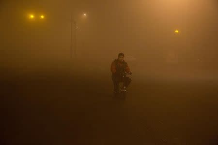 A man smokes as he rides in smog during polluted day in Beijing, China, December 20, 2016. REUTERS/Stringer