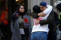 WeWork employees embrace on the sidewalk outside the entrance to the WeWork corporate headquarters in Manhattan, New York